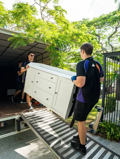 Two SwiftMove movers carrying a white chest of drawers onto a truck