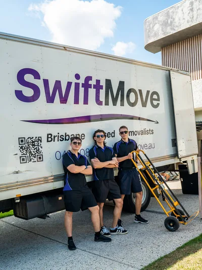 Three SwiftMove movers with a trolley beside their truck