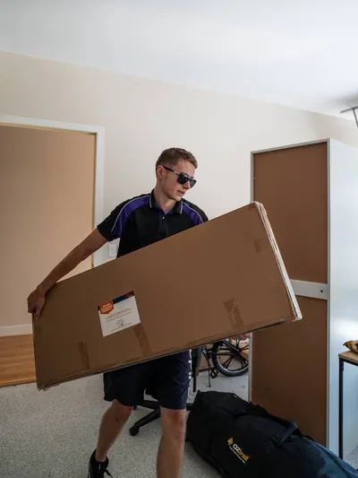 SwiftMove mover carrying a large carton inside a Brisbane home